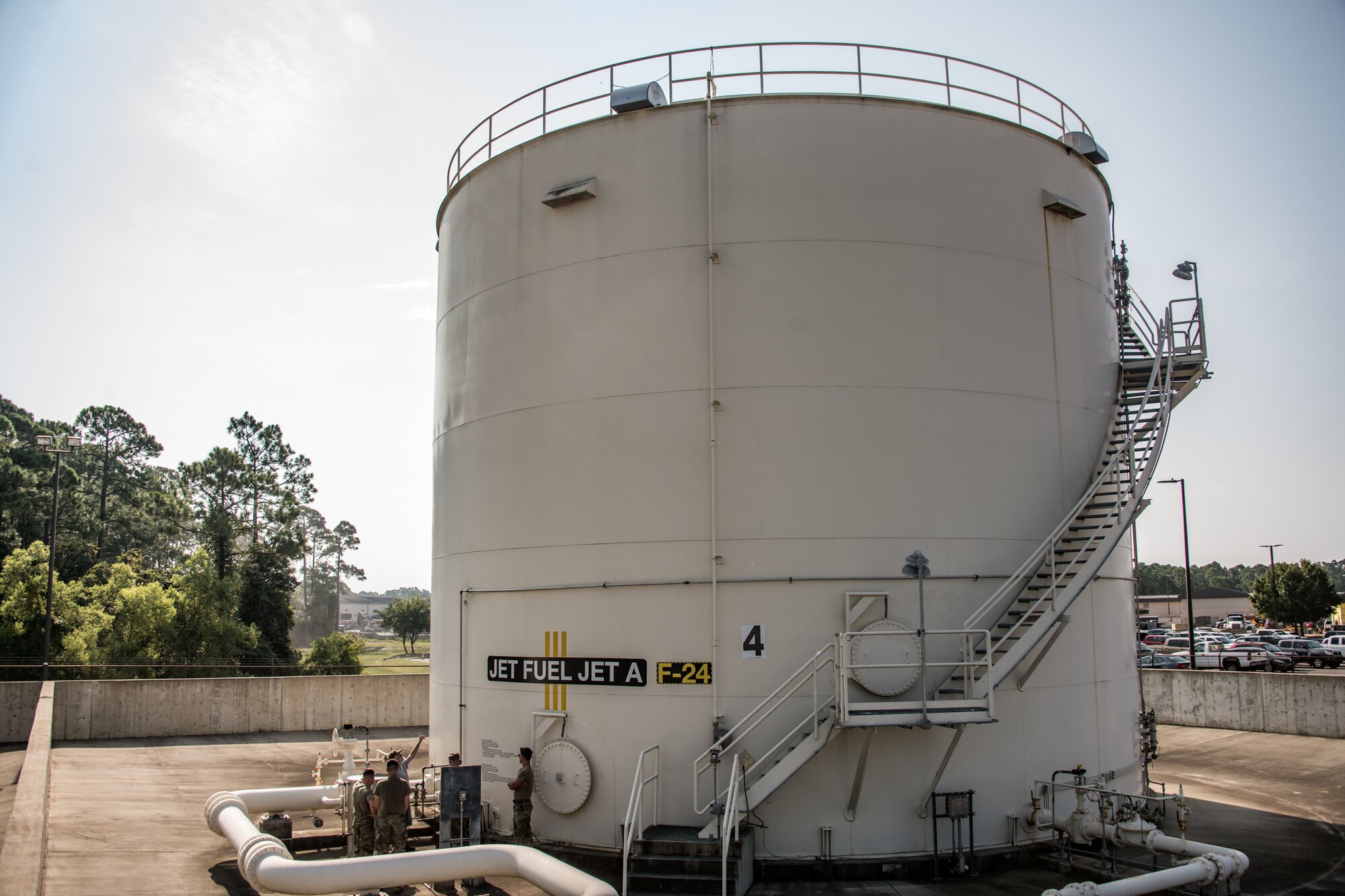 Five men tour the exterior of an above ground fuel storage tank