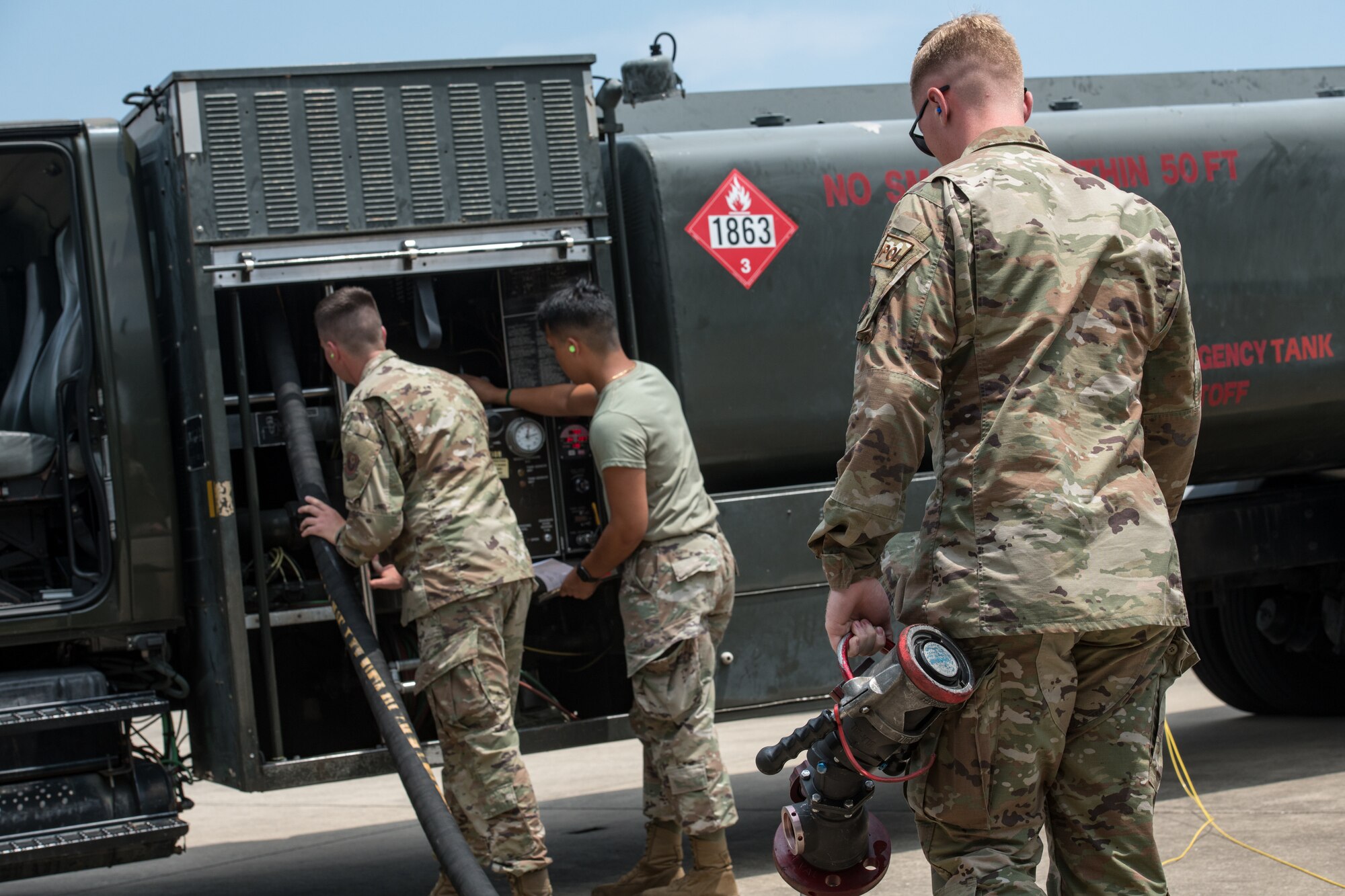 Men move a fuel hose back onto a truck