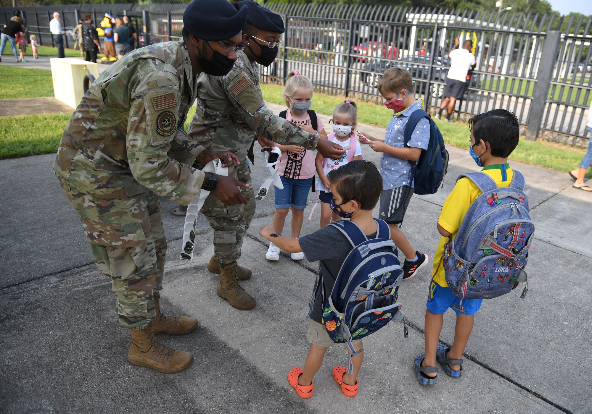 U.S. Air Force Airman 1st Class LaDarian Carter, 81st Security Forces Squadron base defense operations center controller, and Senior Airman Jocilyn Carver, 81st SFS entry controller, passes out stickers to military children at Keesler Air Force Base, Mississippi, Aug. 4, 2021. Members from the 81st SFS greeted children as they went to Jeff Davis Elementary School on their first day of school. (U.S. Air Force photo by Kemberly Groue)