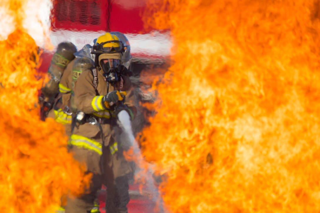 A firefighter trains a hose on a fire.