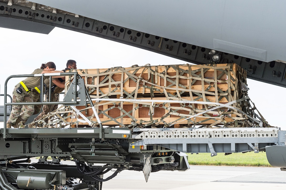 Airmen push a pallet into an open aircraft.