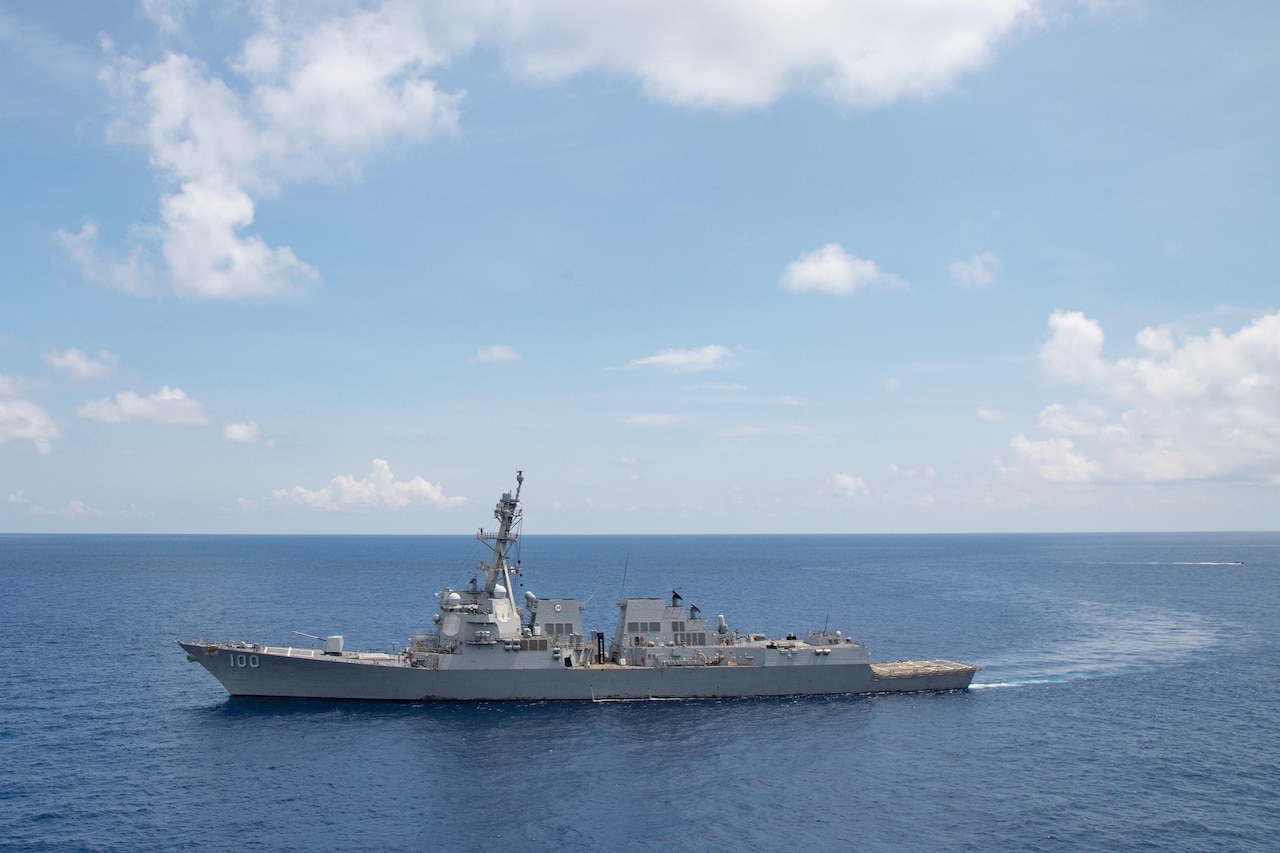 A large grey boat moves through the ocean.