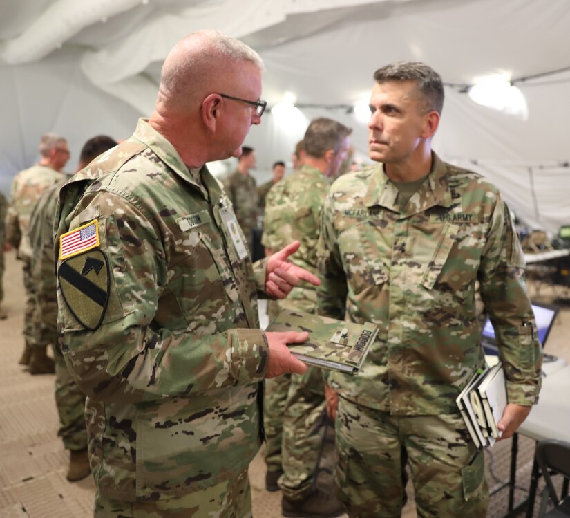 Brig. Gen. Gen. Jeffrey C. Coggin (left), commanding general of the U.S. Army Civil Affairs and Psychological Operations Command (Airborne), speaks with Maj. Gen. Matthew McFarlane, Commanding General, 4th Infantry Division, as they participate in the Joint Warfighting Assessment 2021 distinguished visitor day initial briefing at Fort Carson, Colo., June 25, 2021. U.S. Army Civil Affairs and Psychological Operations Command (Airborne) Civil Affairs, Psychological Operations, and Information Operations Soldiers took part in JWA 2021 with participants from different Army units and multinational partners such as U.K., Australian and Canadian armed forces, working to improve interoperability between U.S. joint forces and our allies. JWA exercises help the Army evaluate emerging concepts, integrate new technologies, and promote interoperability between the Army, other services, and our multinational partners. Joint and multinational partners are key to the success of Multi-Domain Operations.