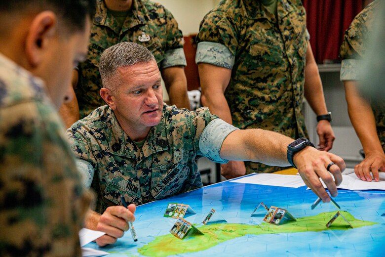 U.S. Marine Corps Gunnery Sgt. Richard Ison, the aviation life support coordinator with Marine Wing Headquarters Squadron 1, 1st Marine Aircraft Wing, collaborates and engages in a littoral war game on Camp Hansen, Okinawa, Japan, July 29, 2021. Using predictive analytical tools, critical decision making, and feasibility of support, students attending the Advanced Course at the Staff Noncommissioned Officer Academy used a littoral war game to combine their diverse backgrounds and simulate various sea-based operations and strategies. (U.S. Marine Corps photo by Lance Cpl. Alex Fairchild)