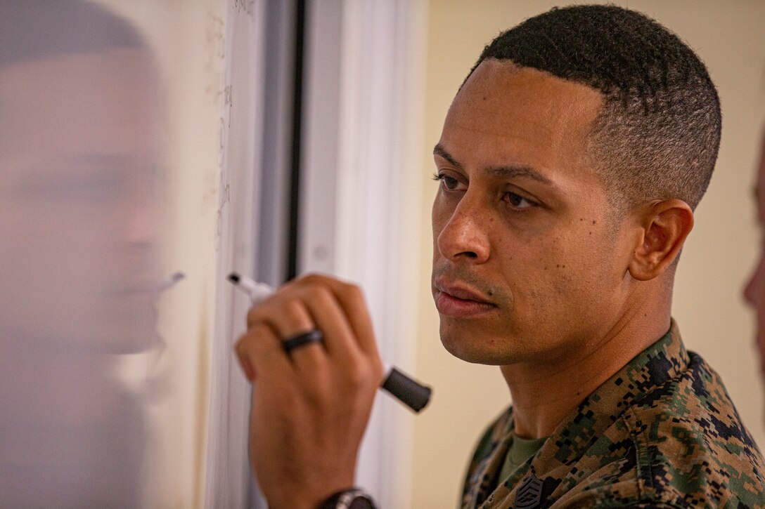 U.S. Marine Corps Gunnery Sgt. Bruce Jones, the substance abuse coordinating officer with Headquarters and Support Battalion, Marine Corps Installations Pacific, plans a strategy during a littoral war game on Camp Hansen, Okinawa, Japan, July 29, 2021. Jones is a native of Shreveport, Louisiana. Using predictive analytical tools, critical decision making, and feasibility of support, students attending the Advanced Course at the SNCOA used a littoral war game to combine their diverse backgrounds and simulate various sea-based operations and strategies. (U.S. Marine Corps photo by Lance Cpl. Alex Fairchild)