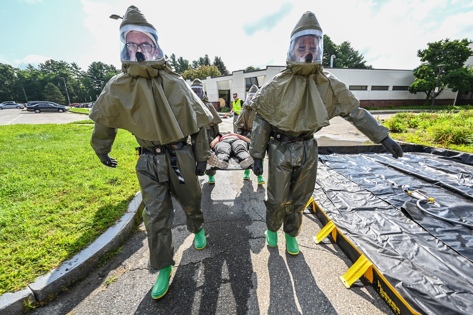 66th Medical Squadron In-Place Patient Decontamination Team members Senior Airmen Gavin Fluery and Ezekiel Grogan, carry an injured role player, Staff Sgt. Leilanie Kenley, 66th Security Forces Squadron NCO in charge of commander support staff, to a decontamination tent during a Ready Eagle exercise at Hanscom Air Force Base, Mass., July 30. The disaster response exercise prepared MDS staff to respond to chemical, biological, radiological, nuclear, or explosive incidents. (U.S. Air Force photo by Todd Maki)