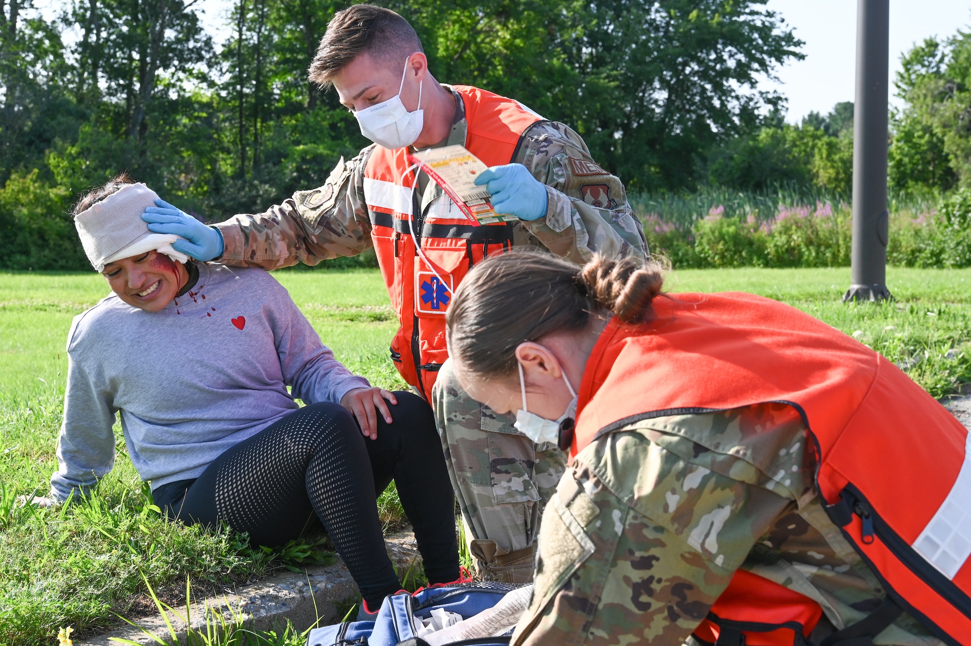 66th Medical Squadron Field Response Team members Tech. Sgts. William Trimble and Tatiana Lieback provide support to an injured role player, Tech. Sgt. Kelly Portillo, Air Force Life Cycle Management Center, Detachment 7 Commander Support Staff section chief, during a Ready Eagle exercise at Hanscom Air Force Base, Mass., July 30. Fifty volunteers from installations around New England donned moulage injuries to authenticate the training. (U.S. Air Force photo by Todd Maki)