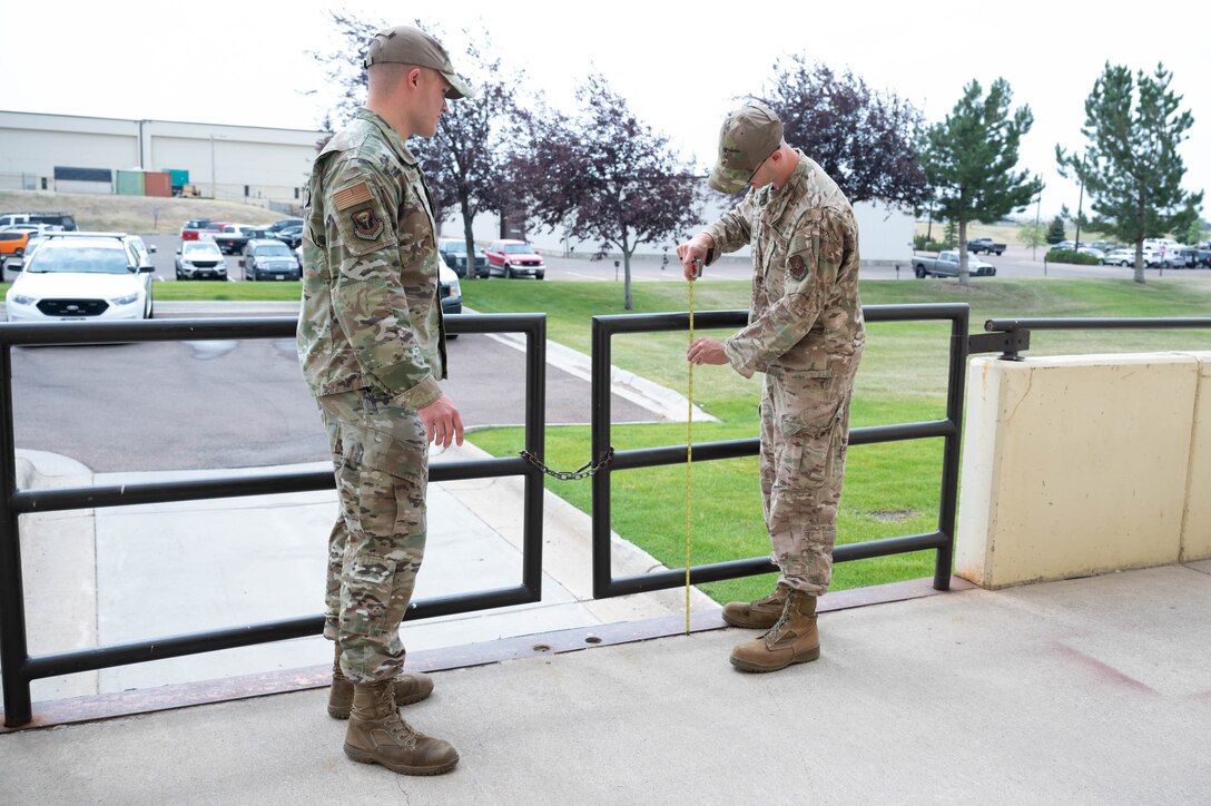 Staff Sgt. Justin Manning, left, 341st Missile Wing occupational safety technician, and Tech. Sgt. Mark Allen, right, 341st MW occupational safety NCO in charge, measure the height of a loading dock gate Aug. 2, 2021, at Malmstrom Air Force Base, Mont.