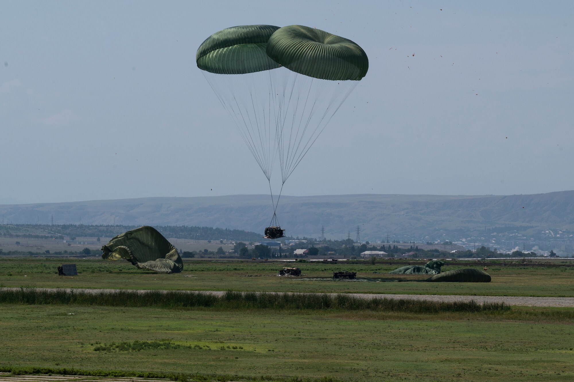 Heavy cargo descends to the ground after being parachuted out of a U.S. Air Force C-130J Super Hercules aircraft during exercise Agile Spirit 21