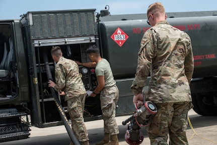 Men move a fuel hose back onto a truck