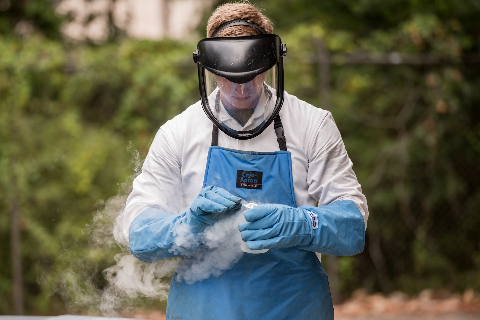 man holds beaker of cryogenic fluid