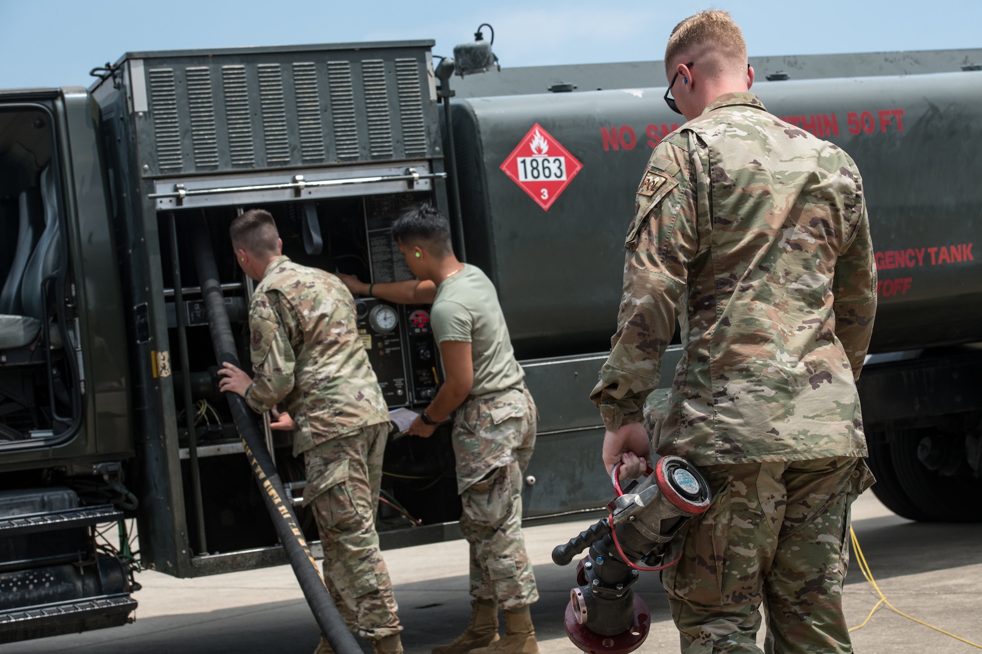 Men move a fuel hose back onto a truck