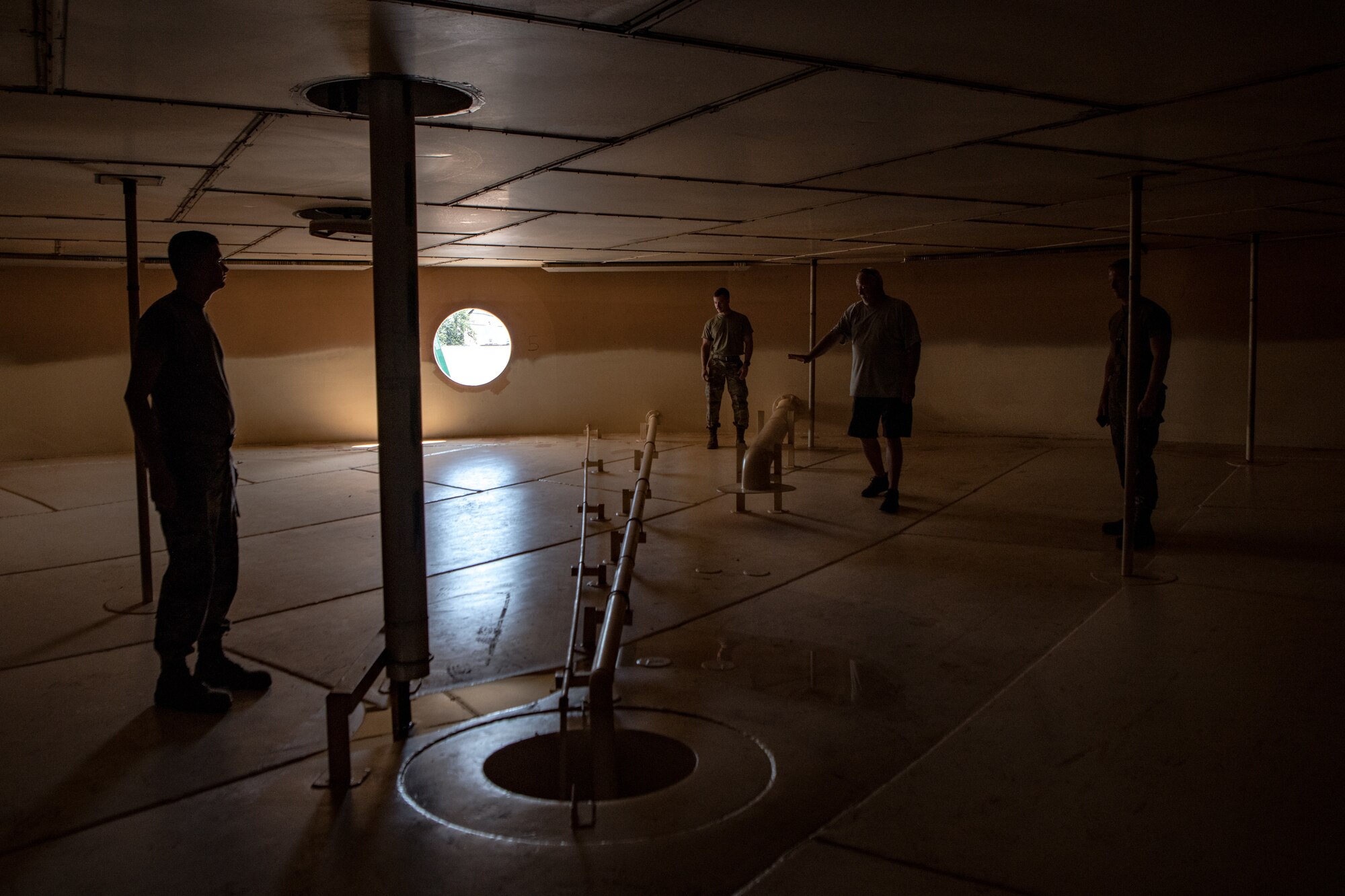 Four men stand inside an above ground fuel tank