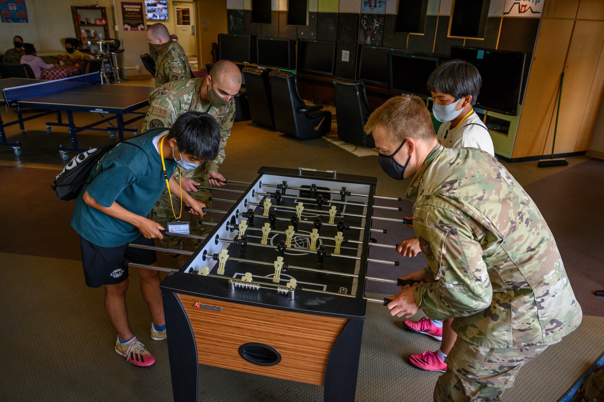 Misawa City English Camp students and 35th Force Support Squadron Airmen play foosball during a base tour at Misawa Air Base, Japan, Aug. 3, 2021. As the students visited the base, they were able to see various work centers, including the 35th Fighter Wing headquarters, 35th Force Support Squadron Misawa Teen Center, 35th Civil Engineer Squadron fire station, Naval Air Facility terminal, Commissary and Base Exchange. (U.S. Air Force photo by Airman 1st Class Antwain Hanks)