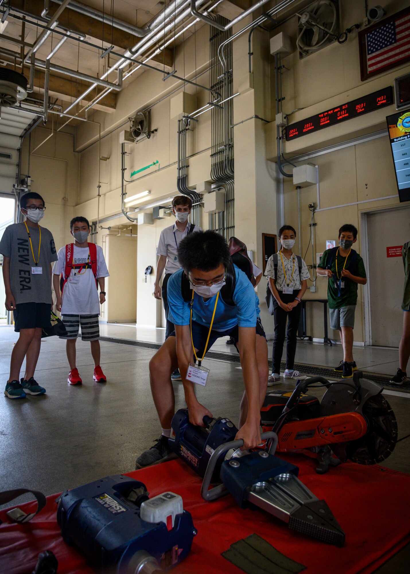 A Misawa City English Camp student picks up a hydraulic rescue tool during a base tour at Misawa Air Base, Japan, Aug. 3, 2021. While touring the fire station, students watched a 35th Civil Engineer Squadron firefighter don his gear and had the chance to don some equipment themselves. (U.S. Air Force photo by Senior Airman China M. Shock)