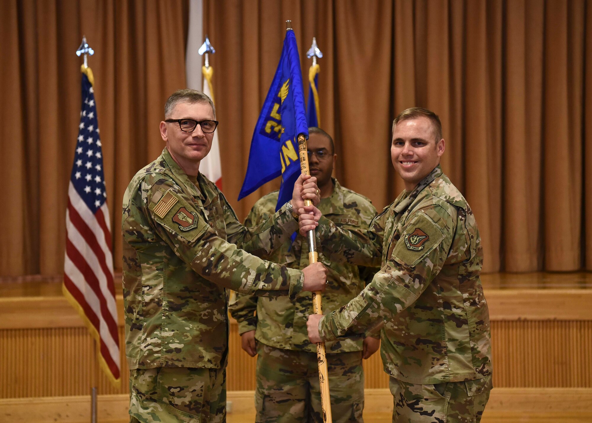 Two military members hold a flag as a part of a ceremony.