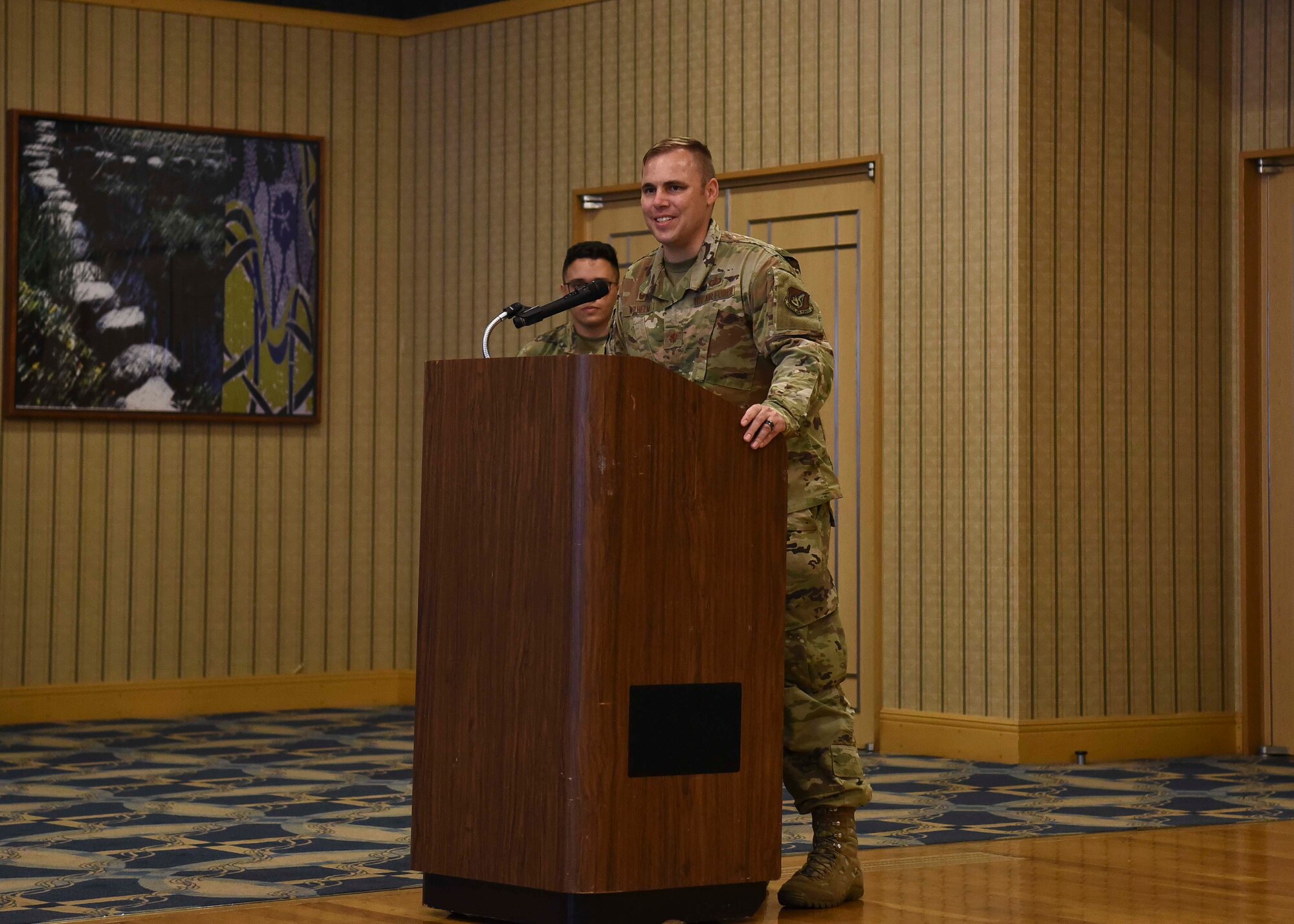 A military member stands behind a podium giving remarks.
