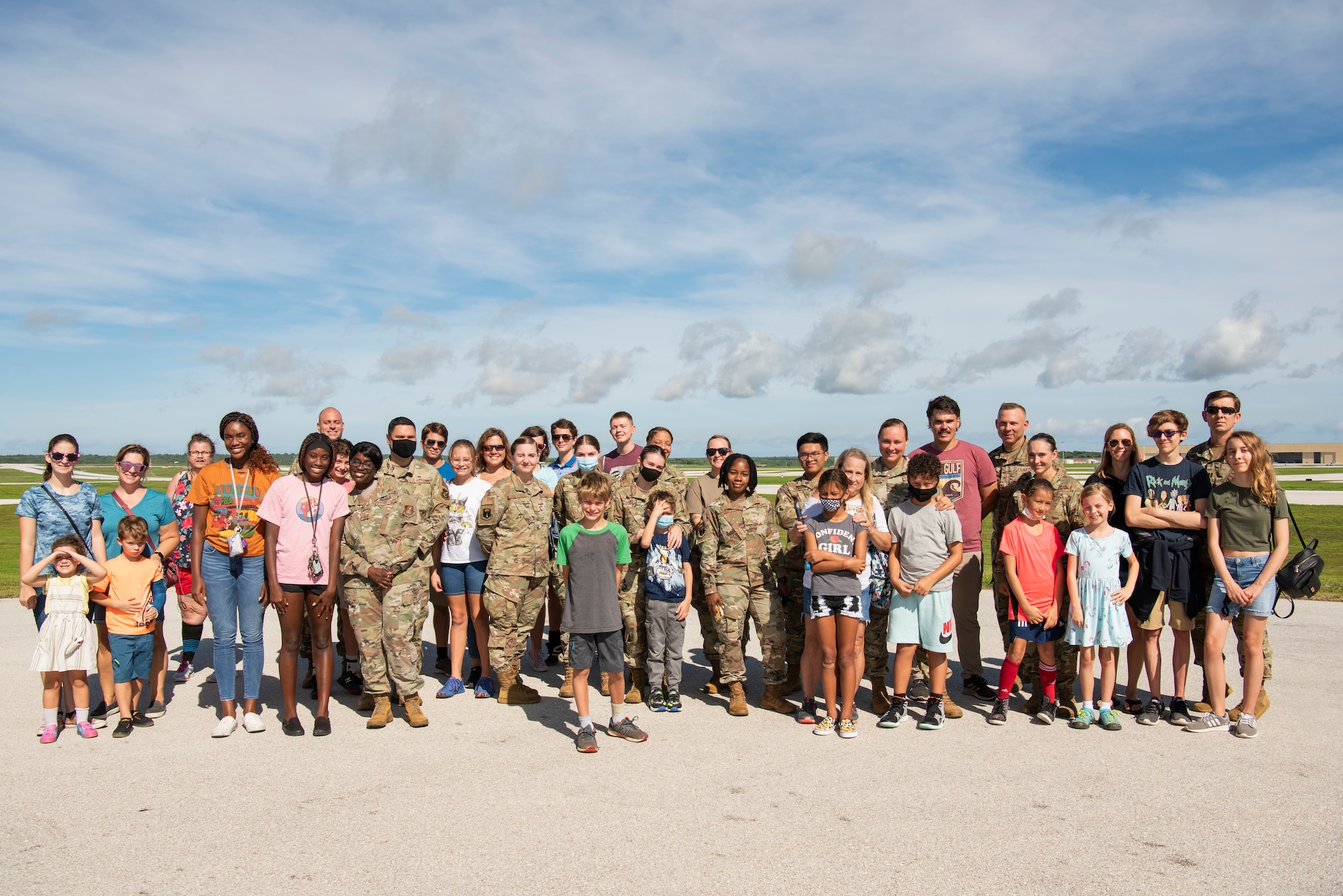 Airmen from the 36th Medical Group come together for a group photo with their families during a flight line engagement for Pacific Iron 2021 at Andersen Air Force Base, Guam, Aug. 4, 2021. The flight line viewing was an opportunity for members assigned to Andersen AFB to see aircraft takeoff up-close and to discuss general aircraft roles, while showcasing the immense effort that it takes to generate airpower. (U.S. Air Force photo by Senior Airman Aubree Owens)