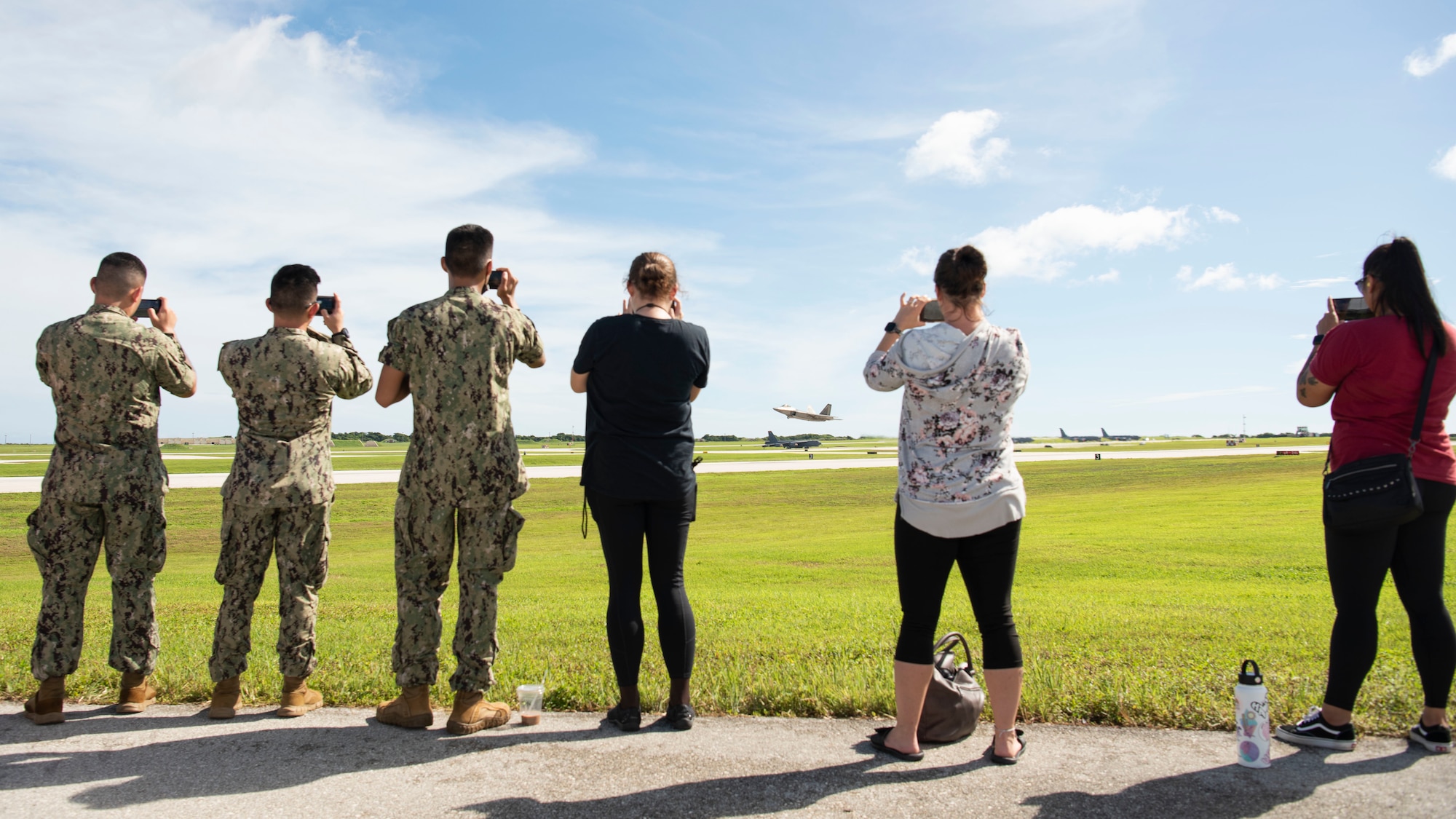 U.S. Navy Sailors and civilian members watch as a U.S. Air Force F-22 Raptor assigned to Joint Base Elmendorf-Richardson, Alaska, takes off during a flight line engagement for Pacific Iron 2021 at Andersen Air Force Base, Guam, Aug. 4, 2021. The flight line viewing was an opportunity to see aircraft takeoff up-close and to discuss general aircraft roles, while showcasing the immense effort that it takes to generate airpower. (U.S. Air Force photo by Senior Airman Aubree Owens)
