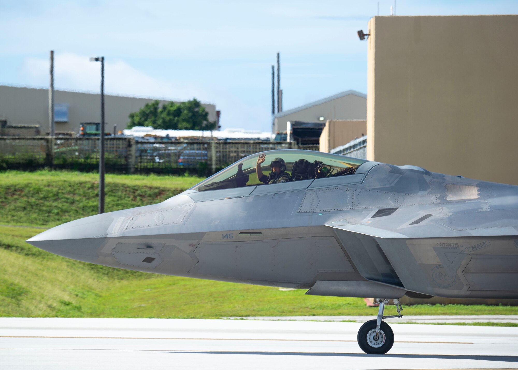 A U.S. Air Force F-22 Raptor Pilot assigned to the 525th Fighter Squadron, Joint Base Elmendorf-Richardson, Alaska, waves to a crowd  during a flight line engagement for Pacific Iron 2021 at Andersen Air Force Base, Guam, Aug. 4, 2021. PACIRON focuses on deploying, operating, and sustaining forces from smaller, dispersed bases in the Indo-Pacific region. A free and open Indo-Pacific region provides prosperity and security for all. (U.S. Air Force photo by Senior Airman Aubree Owens)