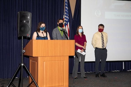 Norfolk Naval Shipyard (NNSY) employees Victoria Pendleton, Derek Metzger, Wendy Cline and Matthew Hahn present their capstone projects at the Code 130 Quality Employee Development Program graduation ceremony.