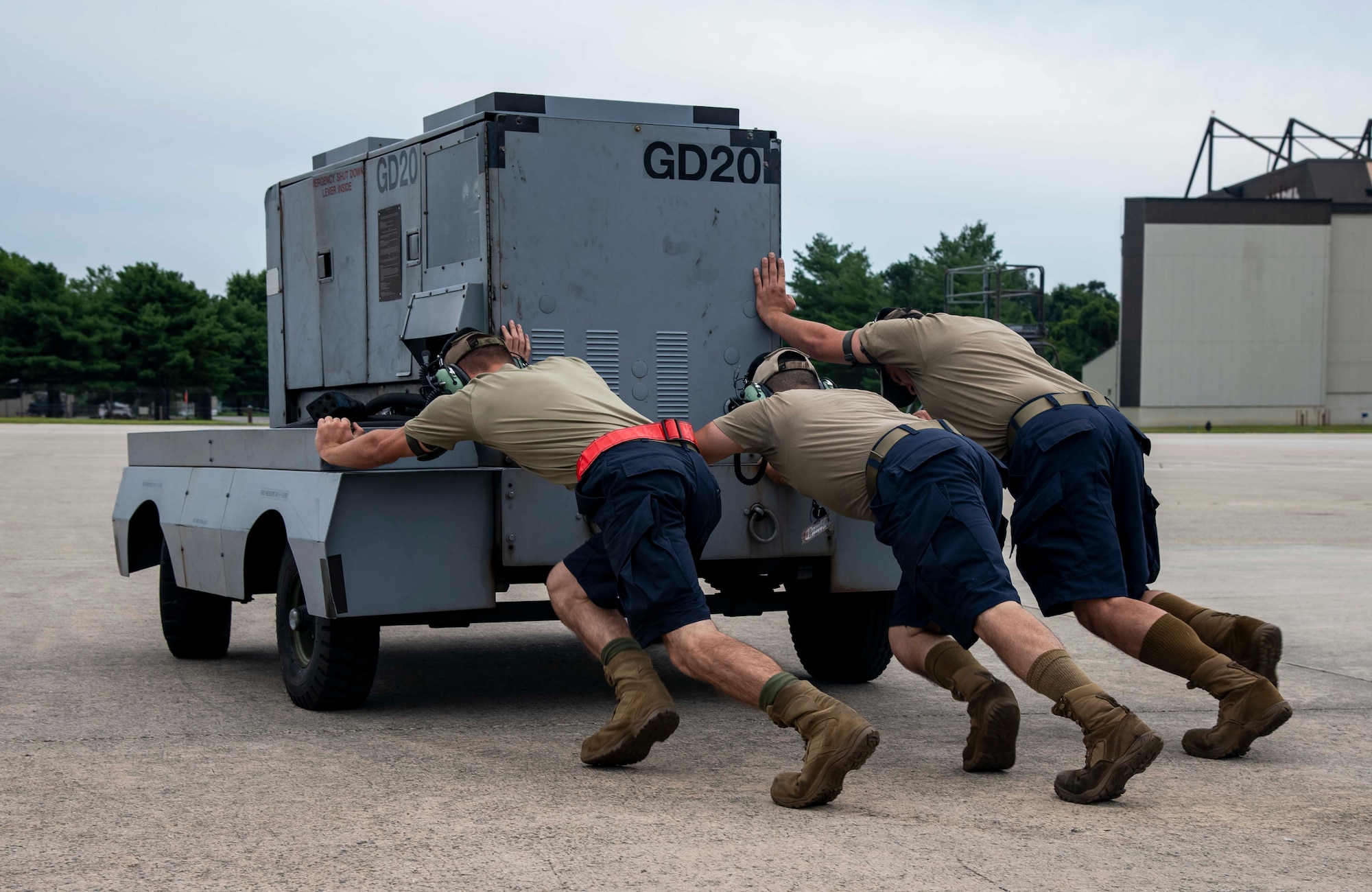 Airmen from the 736th Aircraft Maintenance Squadron push aerospace ground equipment while wearing dark blue shorts at Dover Air Force Base, Delaware, Aug. 4, 2021. According to the modifications of Air Force Instruction 36-2903, maintenance commanders can now authorize Airmen to wear dark blue shorts in place of the Operational Camouflage Pattern trousers when temperatures are expected to meet or exceed 80 degrees Fahrenheit. (U.S. Air Force photo by Senior Airman Stephani Barge)
