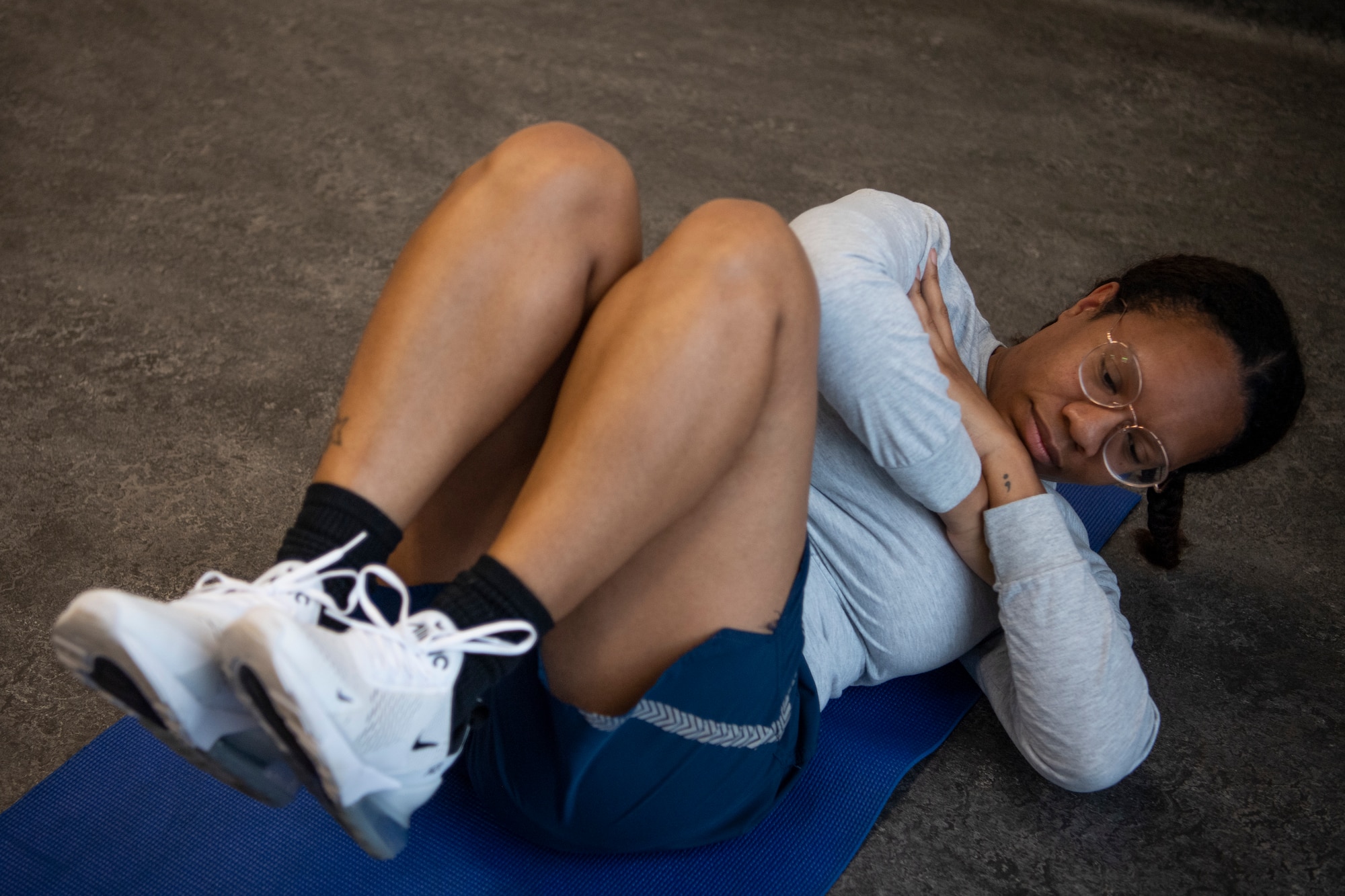 U.S. Air Force Staff Sgt. Brittany Davis, 52nd Aircraft Maintenance Squadron armament weapons system specialist, demonstrates how to perform the cross-leg reverse crunch for USAF physical training testing, Aug. 3, 2021, on Spangdahlem Air Base, Germany. Spangdahlem AB is one of the USAF bases that volunteered to test out the new fitness assessment options, giving members an opportunity to see which methods are their best fit. (U.S. Air Force photo by Staff Sgt. Melody W. Howley)