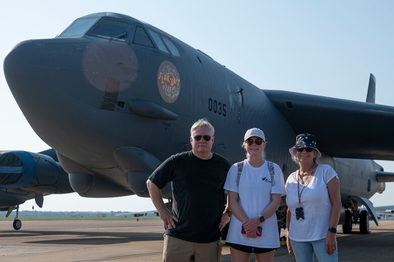 Three people stand smiling in front of an aircraft.