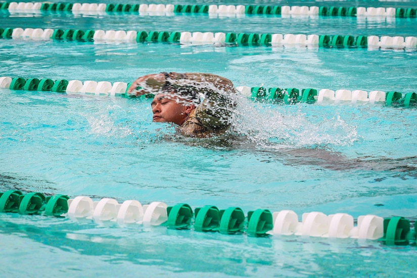 A soldier swims freestyle in a pool.