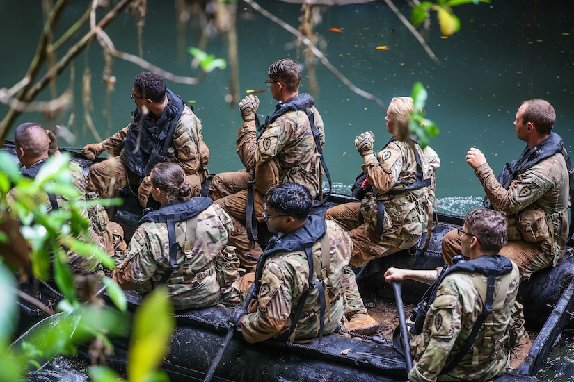 Sailors paddle in a rubber raft.