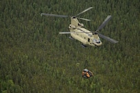 A 211th General Support Aviation Battalion CH-47 Chinook helicopter transports a skid-steer loader by slingload from Nicolai to the community of Telida, Alaska, as part of the Innovative Readiness Training program on July 27, 2021. The IRT program is designed to enhance mission readiness while addressing the needs within America's communities. (U.S. Army National Guard photo by Victoria Granado)