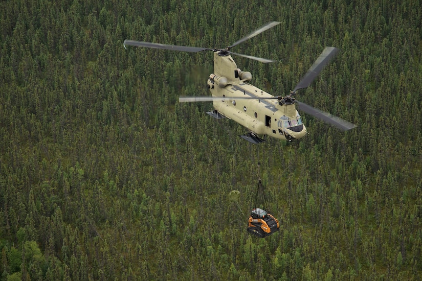 A 211th General Support Aviation Battalion CH-47 Chinook helicopter transports a skid-steer loader by slingload from Nicolai to the community of Telida, Alaska, as part of the Innovative Readiness Training program on July 27, 2021. The IRT program is designed to enhance mission readiness while addressing the needs within America's communities. (U.S. Army National Guard photo by Victoria Granado)
