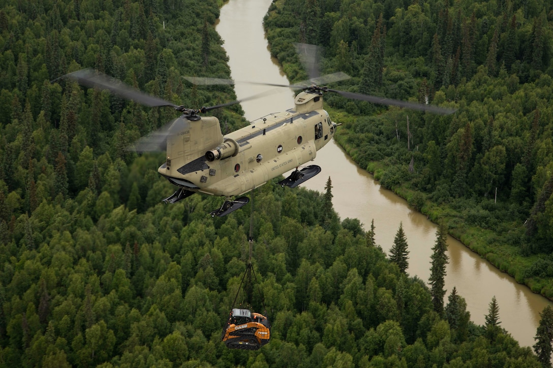 A 211th General Support Aviation Battalion CH-47 Chinook helicopter transports a skid-steer loader by slingload from Nicolai to the community of Telida, Alaska, as part of the Innovative Readiness Training program on July 27, 2021. The IRT program is designed to enhance mission readiness while addressing the needs within America's communities. (U.S. Army National Guard photo by Victoria Granado)