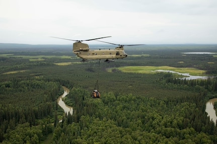 A 211th General Support Aviation Battalion CH-47 Chinook helicopter transports a skid-steer loader by slingload from Nicolai to the community of Telida, Alaska, as part of the Innovative Readiness Training program on July 27, 2021. The IRT program is designed to enhance mission readiness while addressing the needs within America's communities. (U.S. Army National Guard photo by Victoria Granado)