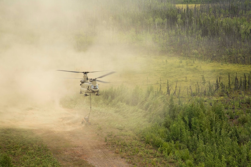 A 211th General Support Aviation Battalion CH-47 Chinook helicopter transports a skid-steer loader by slingload from Nicolai to the community of Telida, Alaska, as part of the Innovative Readiness Training program on July 27, 2021. The IRT program is designed to enhance mission readiness while addressing the needs within America's communities. (U.S. Army National Guard photo by Victoria Granado)