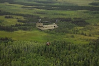 A 211th General Support Aviation Battalion CH-47 Chinook helicopter transports a skid-steer loader by slingload from Nicolai to the community of Telida, Alaska, as part of the Innovative Readiness Training program on July 27, 2021. The IRT program is designed to enhance mission readiness while addressing the needs within America's communities. (U.S. Army National Guard photo by Victoria Granado)