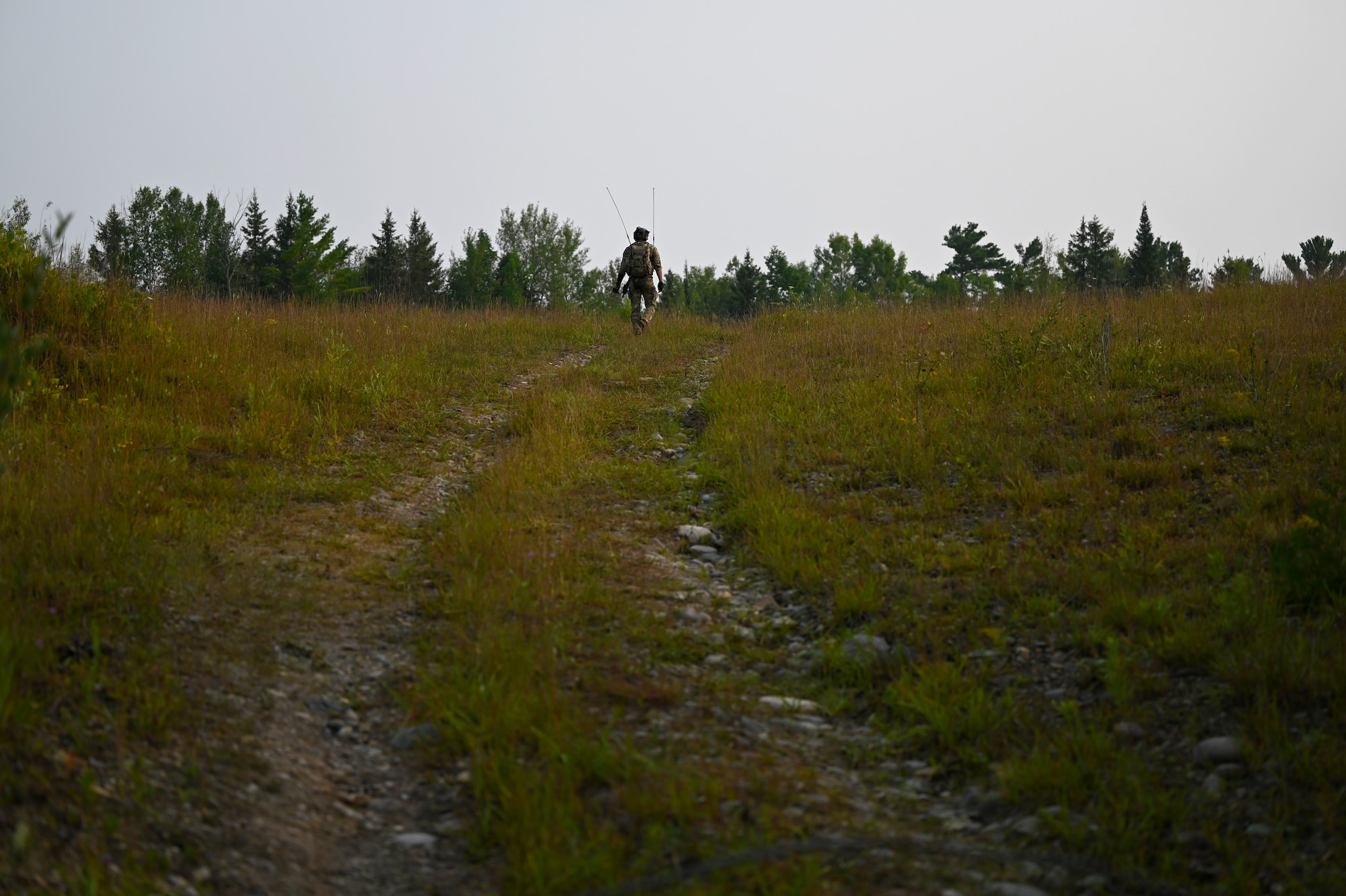 A Special Tactics operator from the 24th Special Operations Wing walks up a hill in order to receive radio signal while surveying and preparing a closed section of U.S. Highway 32 to land and receive aircraft during exercise Northern Strike 21 Aug. 5, 2021, at Alpena, Mich. Special Tactics Airmen are the Air Force’s special operations ground force, experienced in conducting global access missions such as establishing austere landing zones around the world.   (U.S. Air Force photo by Staff. Sgt Ridge Shan)