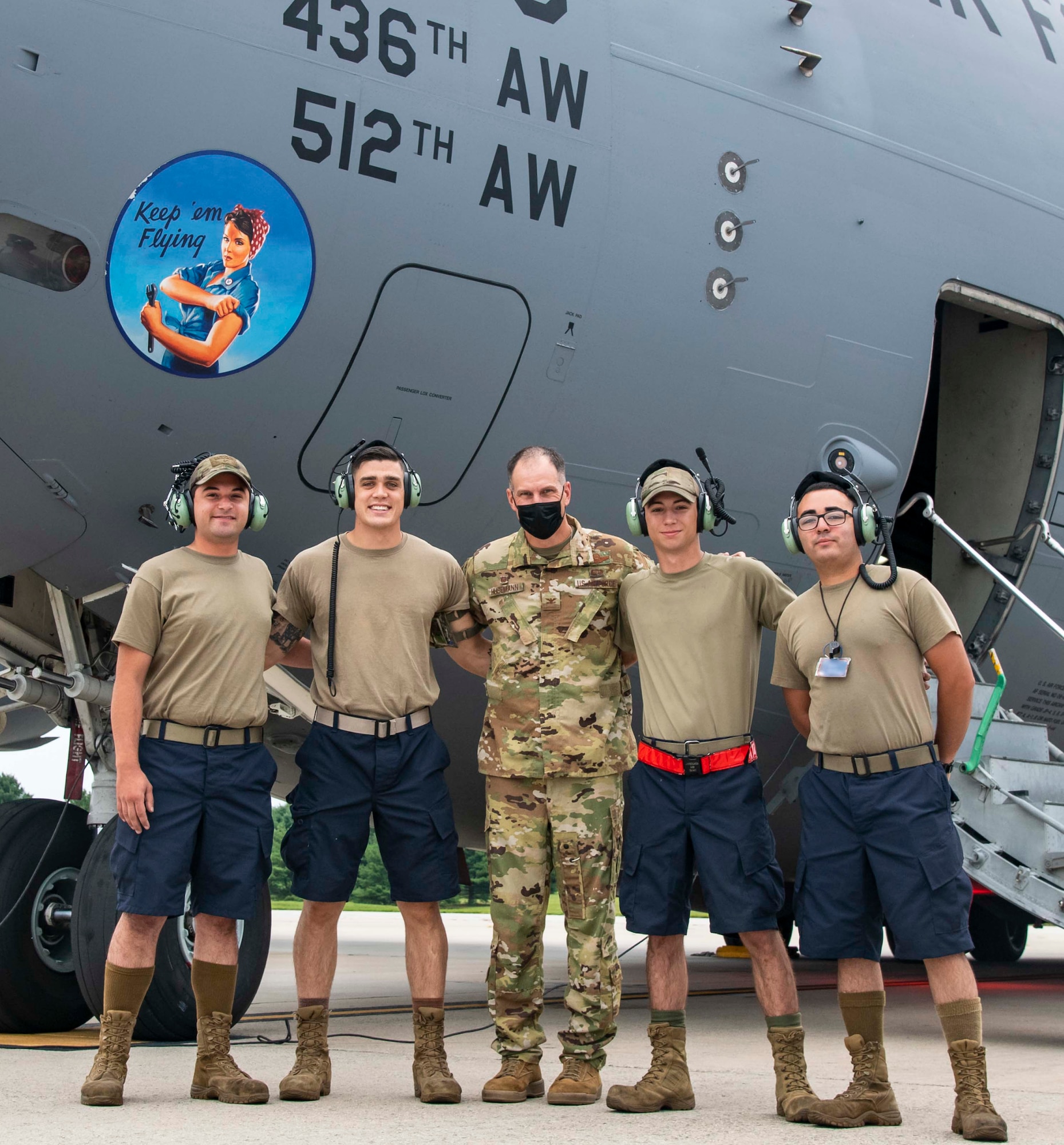 Col. Matt Husemann, center, 436th Airlift Wing commander, poses for a photo with Airmen from the 736th Aircraft Maintenance Squadron at Dover Air Force Base, Delaware, Aug. 4, 2021. According to the modifications of Air Force Instruction 36-2903, maintenance commanders can now authorize Airmen to wear dark blue shorts in place of the Operational Camouflage Pattern trousers when temperatures are expected to meet or exceed 80 degrees Fahrenheit. (This image has been altered for security purposes to blur out an identification badge) (U.S. Air Force photo by Senior Airman Stephani Barge)