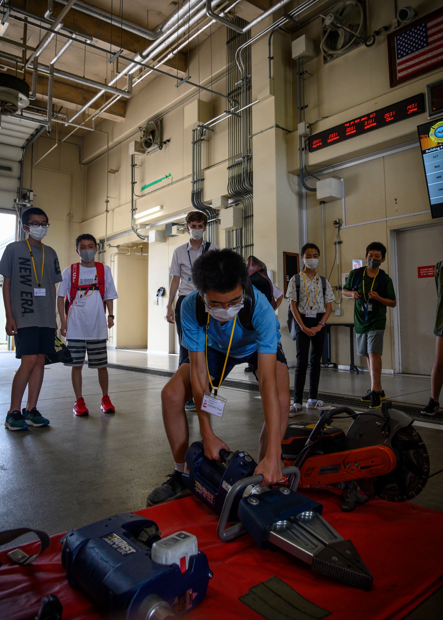 A Misawa City English Camp student picks up a hydraulic rescue tool during a base tour at Misawa Air Base, Japan, Aug. 3, 2021. While touring the fire station, students watched a 35th Civil Engineer Squadron firefighter don his gear and had the chance to don some equipment themselves. (U.S. Air Force photo by Senior Airman China M. Shock)