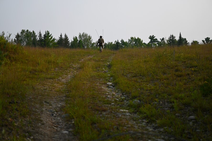A Special Tactics operator from the 24th Special Operations Wing walks up a hill in order to receive radio signal while surveying and preparing a closed section of U.S. Highway 32 to land and receive aircraft during exercise Northern Strike 21 Aug. 5, 2021, at Alpena, Mich. Special Tactics Airmen are the Air Force’s special operations ground force, experienced in conducting global access missions such as establishing austere landing zones around the world.   (U.S. Air Force photo by Staff. Sgt Ridge Shan)