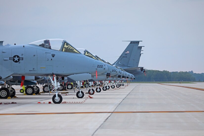 Military aircraft sit in a long line on a tarmac.