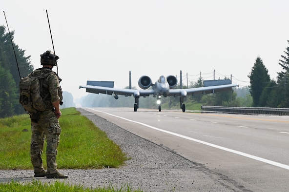 A special tactics operator from the 24th Special Operations Wing guides an A-10 Thunderbolt II from the Michigan Air National Guard’s 127th Wing as it lands on a closed public highway Aug. 5, 2021 at Alpena, Mich., as part of a training exercise during Northern Strike 21. This is the first time in history that the Air Force has purposely landed modern aircraft on a civilian roadway in the U.S. The joint training event tested part of the agile employment concept, focusing on projecting combat power from austere locations. (U.S. Air Force photo by Staff Sgt. Ridge Shan)