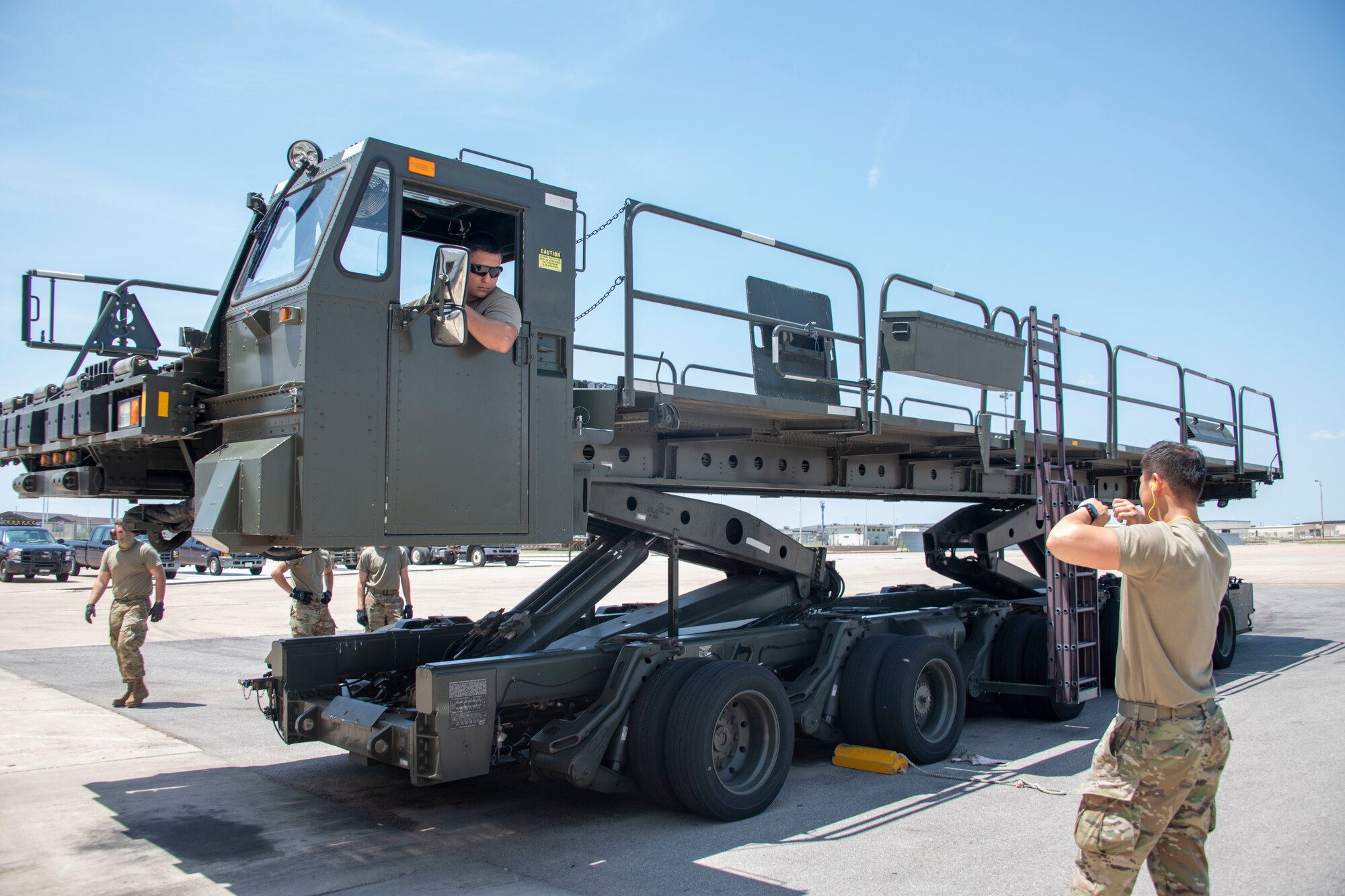 U.S. Air Force Senior Airman Sangwook Han, 97th Logistics Readiness Squadron (LRS) air freight journeyman, directs Senior Airman Kysen Garcia, 97th LRS aircraft services specialist, to stop the lowering of a Tunner 60K Aircraft Cargo Loader/Transporter at Altus Air Force Base, Oklahoma, July 27, 2021.