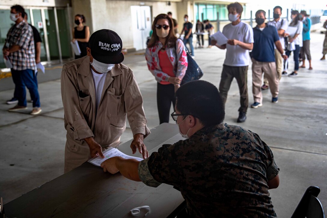 沖縄県北谷町にある米海兵隊基地キャンプ・フォスターの中にある米海軍病院で、新型コロナワクチン接種を受けるために予約を確認する日本人従業員と米軍関係者