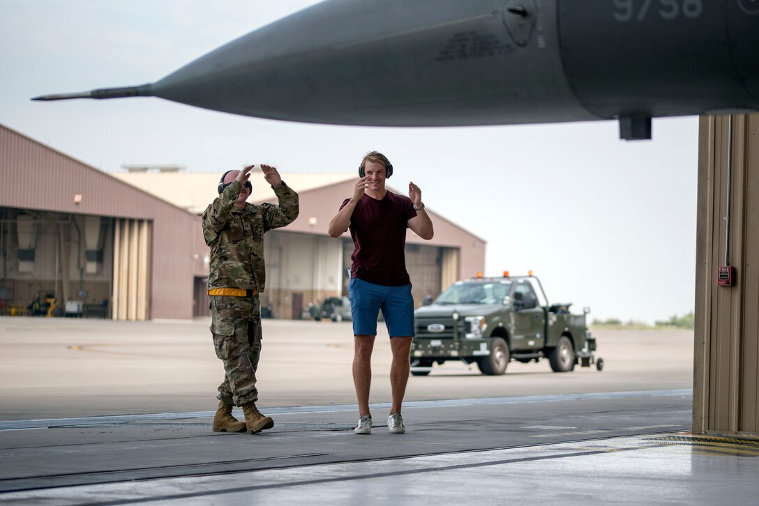 Scott Mayfield, NHL New York Islanders hockey player, helps Tech. Sgt. Timothy Marr, 849th Aircraft Maintenance Squadron flight line expediter, marshal an F-16 Viper, Aug. 3, 2021, on Holloman Air Force Base, New Mexico. As a part of Mayfield’s familiarization tour, he met with aircraft maintainers and received an up-close tour of the aircraft. (U.S. Air Force photo by Staff Sgt. Christine Groening)