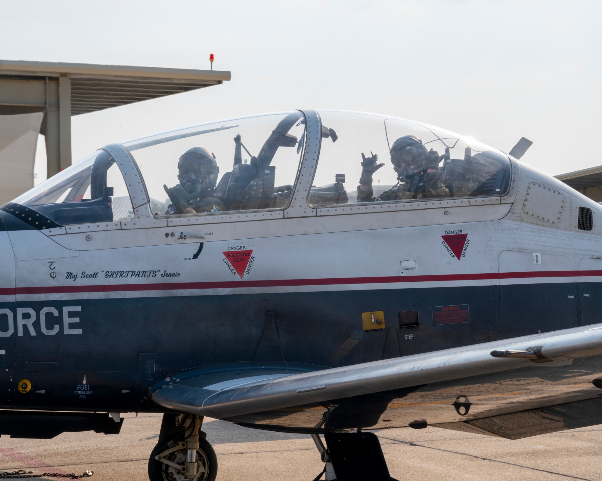 U.S. Air Force 2nd Lt. Christopher Ugale, a student pilot with the 47th Student Squadron, waves to the camera in the cockpit of a T-6 Texan II before his dollar flight with U.S. Air Force Capt. Sarah Fotsch at Laughlin Air Force Base, Texas on August 4, 2021. The Dollar Flight is the first flight in a real aircraft for a student pilot and marks a major milestone in the career of a pilot. (U.S. Air Force Photo by Senior Airman Nicholas Larsen)