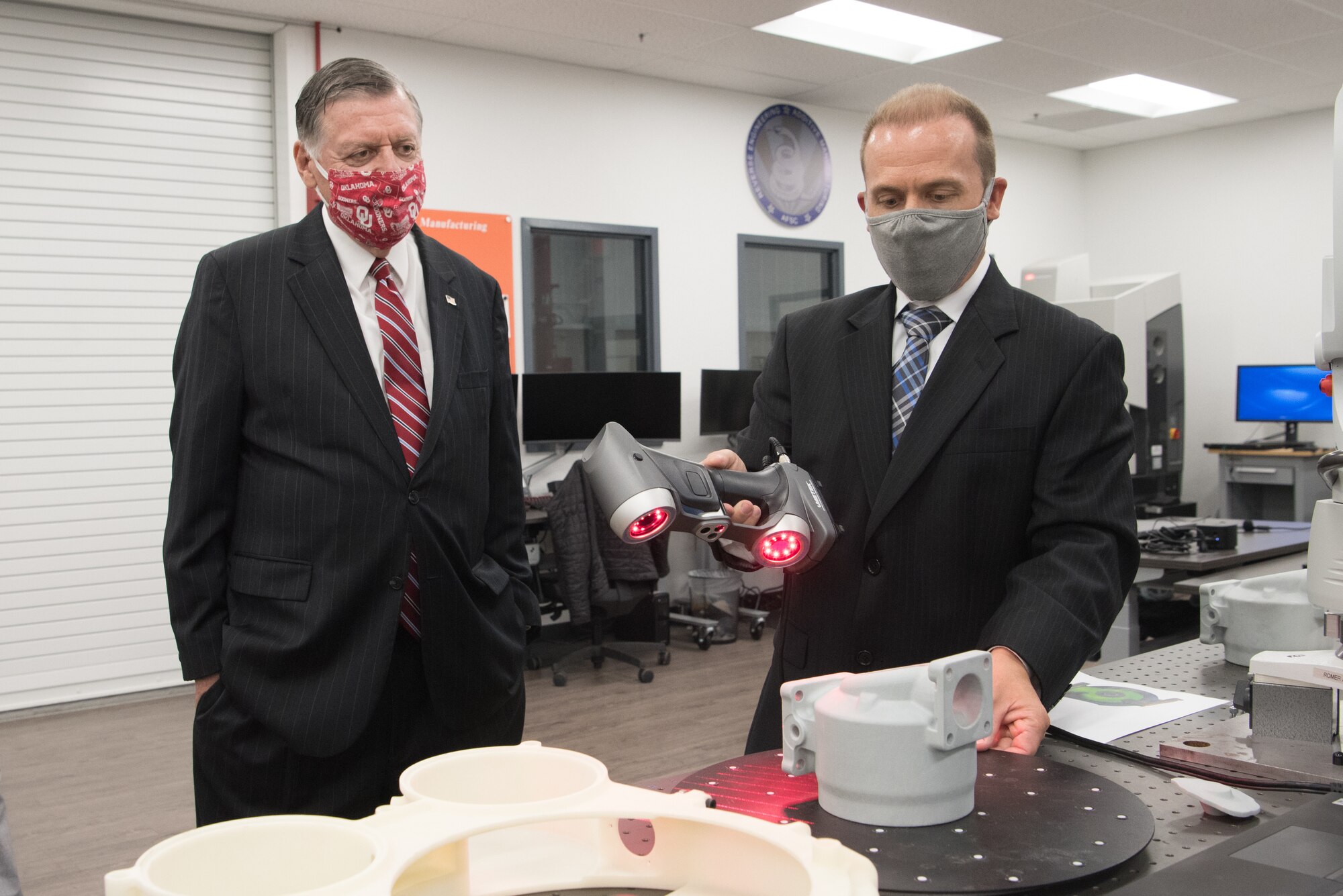 Man watching engineer using 3D scanner.