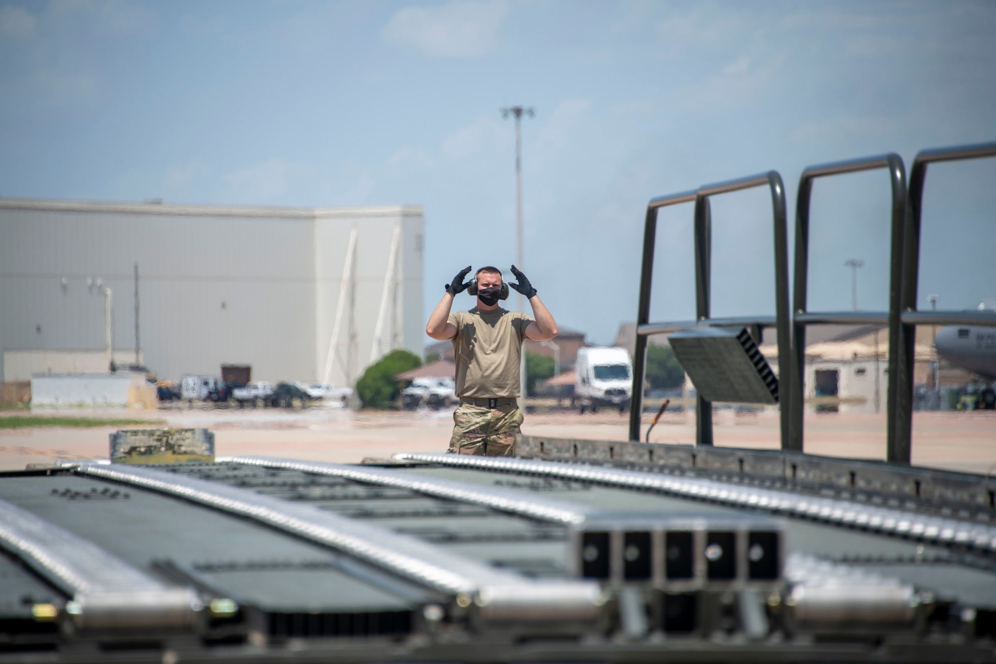 U.S. Air Force Jonathan Garrett, 190th Logistics Readiness Squadron air freight craftsman, directs the driver of a Tunner 60K Aircraft Cargo Loader/Transporter while reversing the vehicle at Altus Air Force Base, Oklahoma, July 27, 2021.