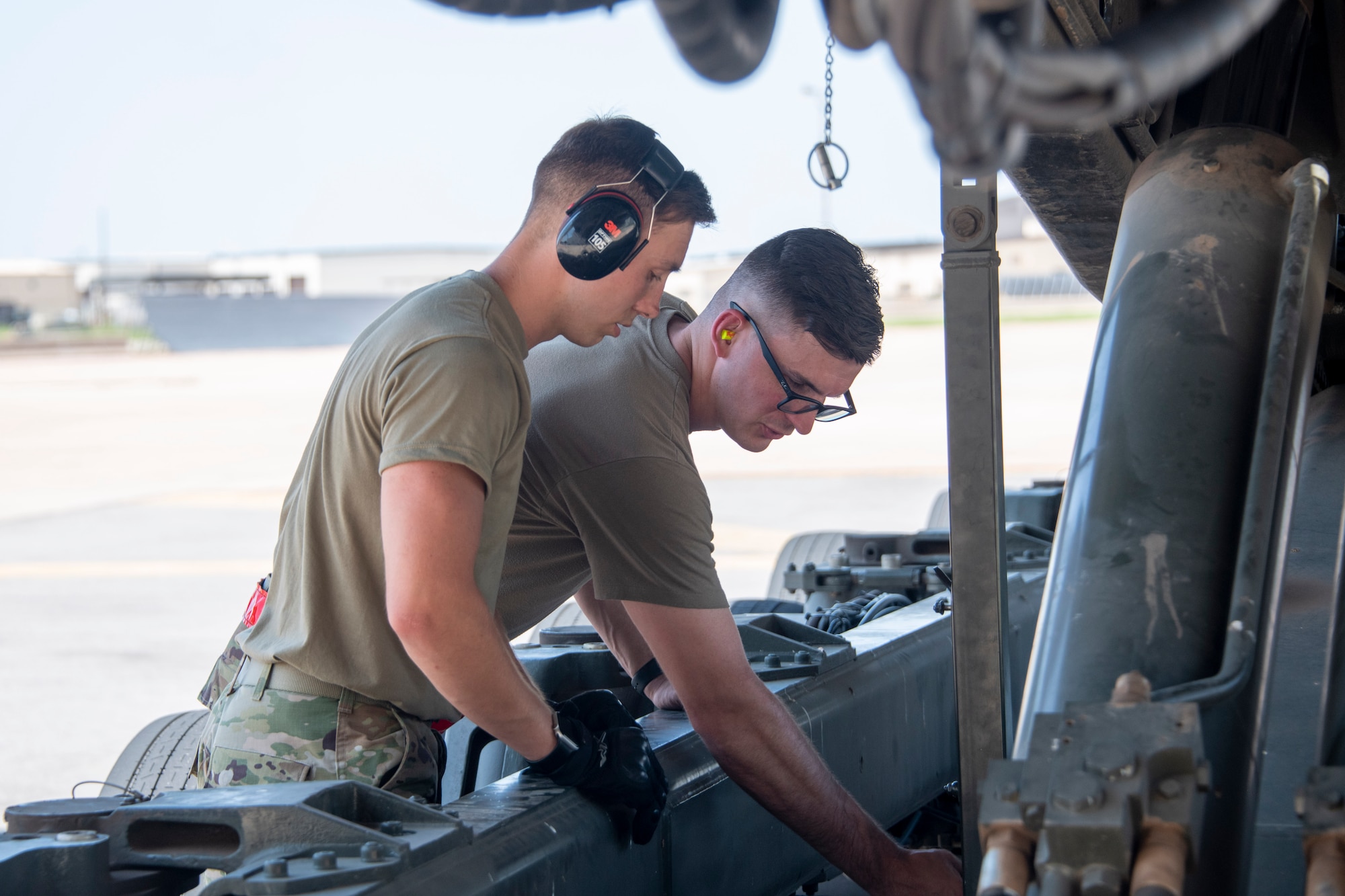 U.S. Air Force Staff Sgt. Spencer Lanston (right), 97th Logistics Readiness Squadron (LRS) air freight supervisor, shows the different parts of the Tunner 60K Aircraft Cargo Loader/Transporter to Senior Airman Ryan Wagner, 190th LRS air freight apprentice at Altus Air Force Base, Oklahoma, July 27, 2021.