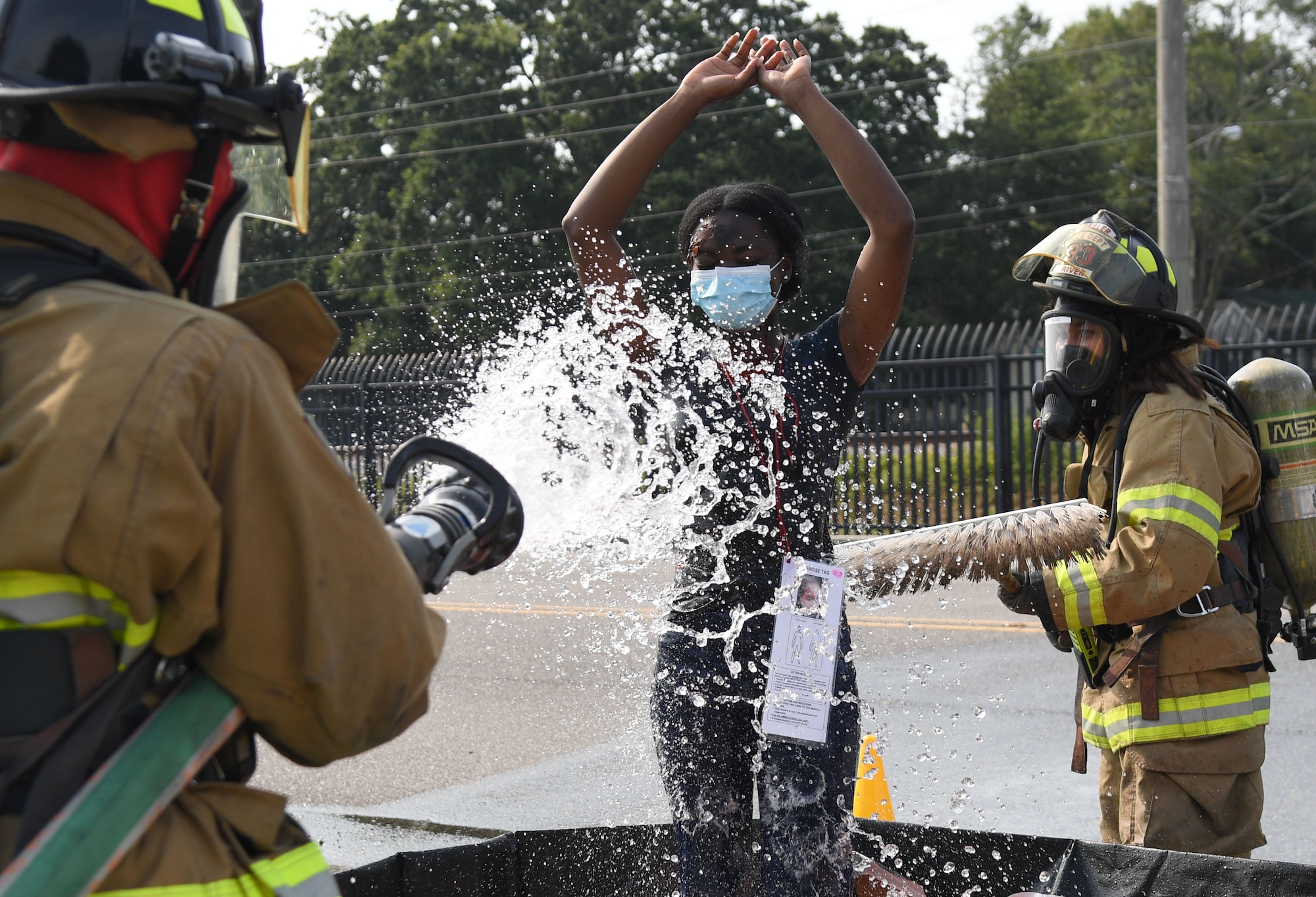 Members of the Keesler fire department decontaminates U.S. Air Force Airman Vera Amponsah, 335th Training Squadron student, as she portrays a victim during a Chemical, Biological, Radiological, Nuclear exercise at Keesler Air Force Base, Mississippi, Aug. 6, 2021. The Ready Eagle exercise tested the base's ability to respond to and recover from a mass casualty event. (U.S. Air Force photo by Kemberly Groue)